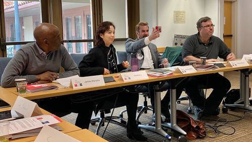 Fei-Fei Li, científica de inteligencia artificial, sentada a una mesa redonda de Stanford HAI junto a un cartel con su nombre, entre otros tres panelistas