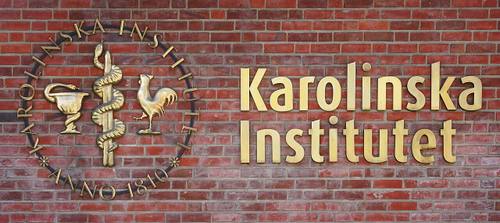 Placa dorada con el emblema y el nombre "Karolinska Institutet, Anno 1810" sobre un muro de ladrillo rojo, en la entrada principal del campus de Solna