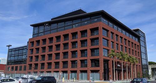 Edificio de ladrillo de la sede de Stripe en San Francisco, con el rótulo "stripe" sobre la entrada y palmeras junto a la puerta principal