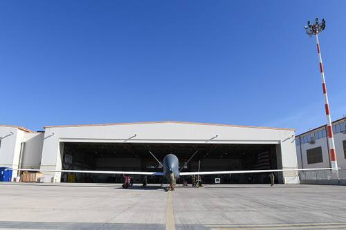 Dron militar de reconocimiento RQ-4 Global Hawk de EE. UU. en pista tras aterrizar, con personal de mantenimiento junto a él en la base de Sigonella, Italia